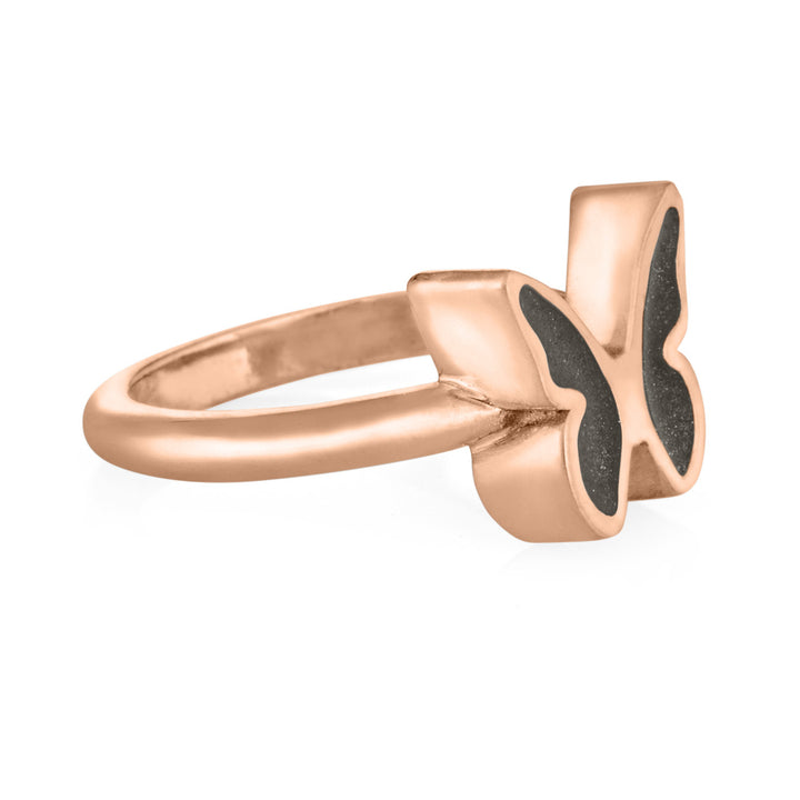 Pictured here is close by me jewelry's 14K Rose Gold Butterfly Cremation Ring with a dark grey ashes setting in each wing from the side to show the depth of the setting and thickness of the band
