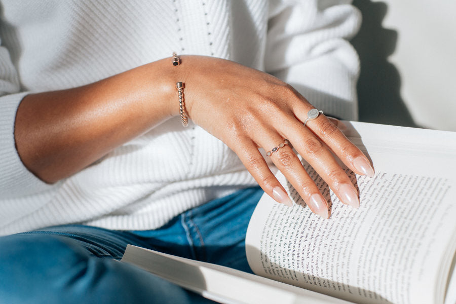 This photo shows a model wearing several pieces of cremains jewelry designed by close by me jewelry. On her index finger, she is wearing the Sterling Silver Cable Band Ashes Ring
