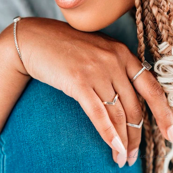 In this photo a model wears close by me jewelry's Chevron Companion Stacking Ring in Sterling Silver as a midi ring on her middle finger