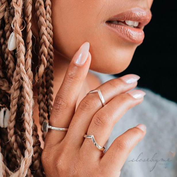 This photo shows a model wearing the Chevron Companion Stacking Ring in Sterling Silver by close by me jewelry on her middle finger as a midi ring