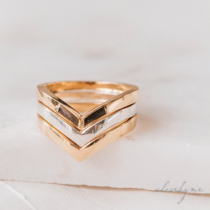 This photo shows several stacked rings by close by me jewelry in mixed metals. The 14K Yellow Gold Chevron Cremation Ring sits on to of a Sterling Silver and 14K Yellow Gold Chevron Companion Ring.
