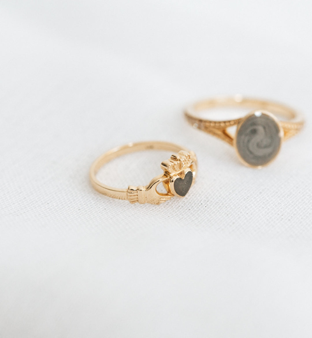 Pictured here is close by me jewelry's 14K Yellow Gold Claddagh Ashes Ring lying flat on a piece of textured white cloth