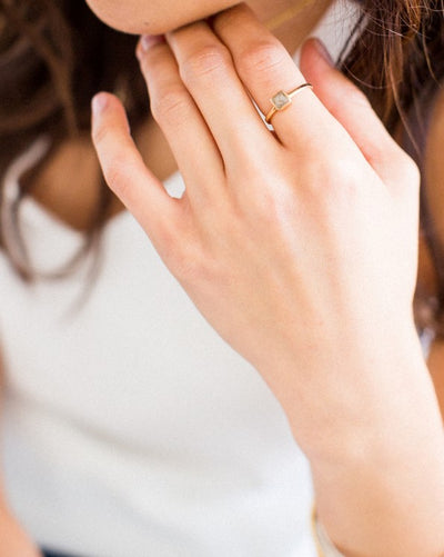 This photo shows a model wearing close by me jewelry's 14K Yellow Gold Dainty Square Ashes Ring on her index finger