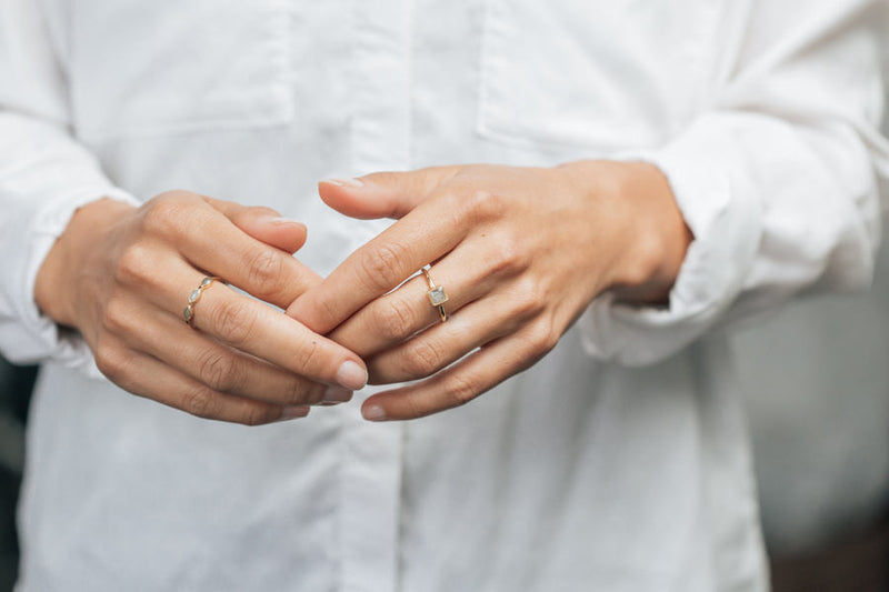 This photo shows a model wearing the 14K Yellow Gold Dainty Square Cremation Ring by close by me jewelry on her middle finger