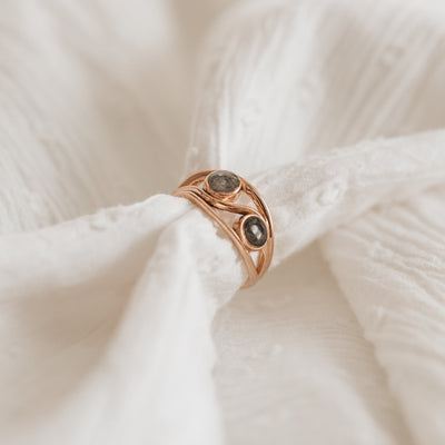 Pictured here is a stylized photo of the Double-Setting Cremation Ring in 14K Rose Gold by close by me jewelry with a soft white cloth going through the band