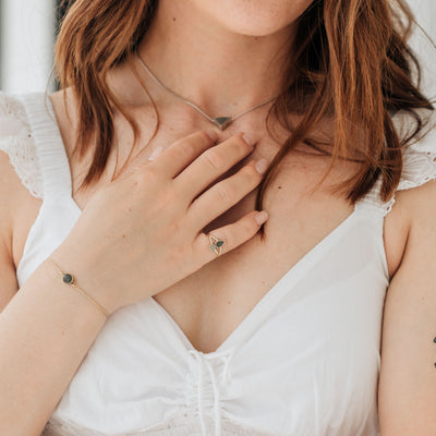 Pictured here is a model wearing several pieces of ashes jewelry designed by close by me jewelry. On her pinky finger, she wears the Double Setting Split Shank Cremation Ring in 14K Yellow Gold