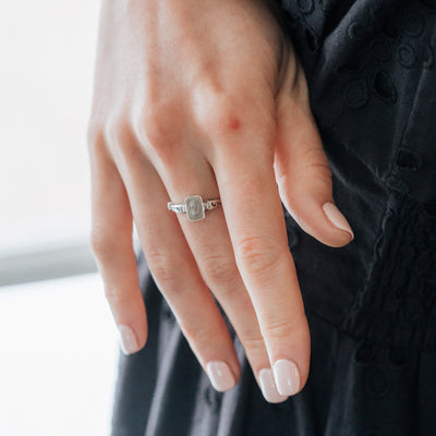 This photo is a close up of a model's hand and the Sterling Silver Emerald Setting Cremation Ring design by close by me jewelry on her middle finger