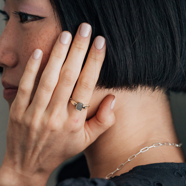 Pictured here is a model wearing close by me jewelry's 14K Yellow Gold Emerald Setting Cremation Ring on her index finger