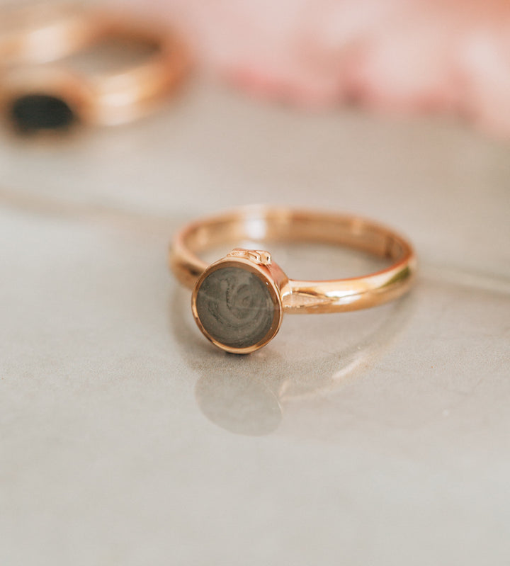 This photo shows the Fleur de Lis Ring by close by me jewelry in 14K Rose Gold with ashes lying flat