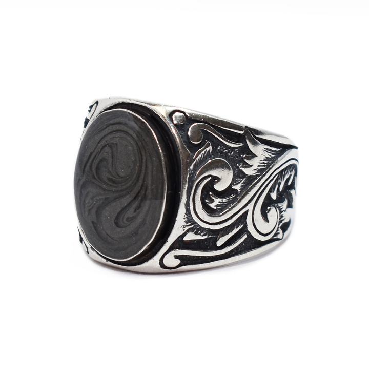 Pictured here is the close by me jewelry's Floral Art Deco Band Cremation Ring in Sterling Silver from an angle to show its dark gray ashes setting and band detail