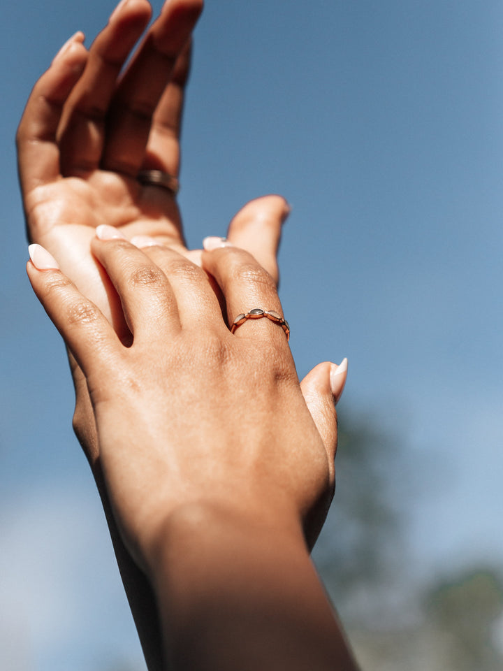 two hands reaching up towards the sky with close by me's four setting cremation ring on model's index finger