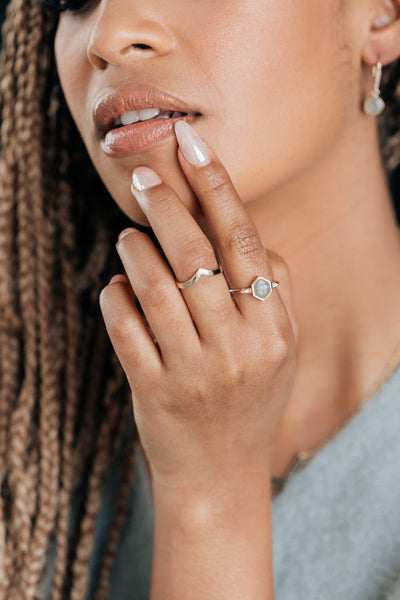 This photo shows a model wearing close by me jewelry's Hexagon White Baguette Diamond Band Cremation Ring in 14K White Gold on her index finger as she touches her bottom lip