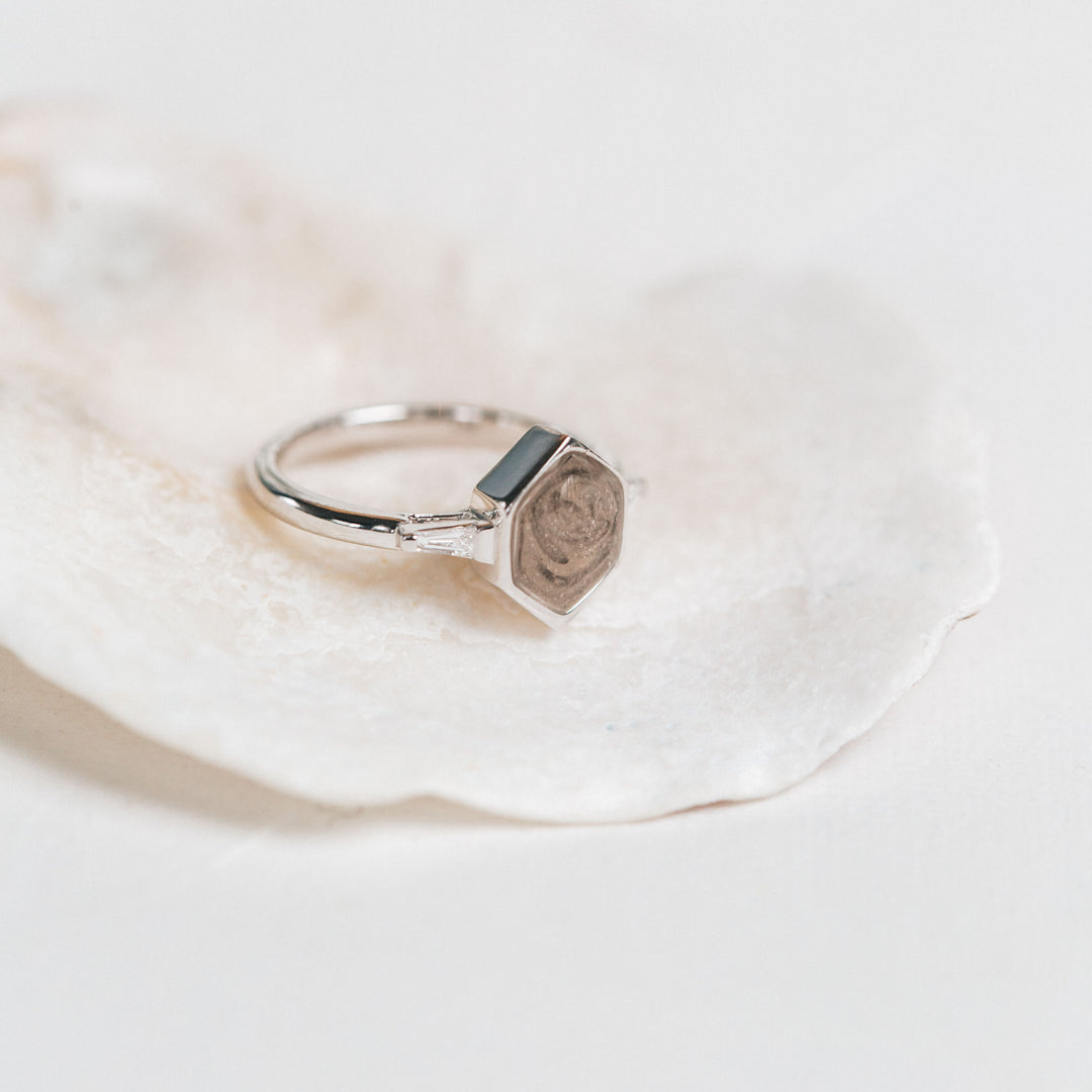 Pictured here is the 14K White Gold Hexagon White Baguette Diamond Band Ring by close by me jewelry on a white shell with a slightly blurry background 