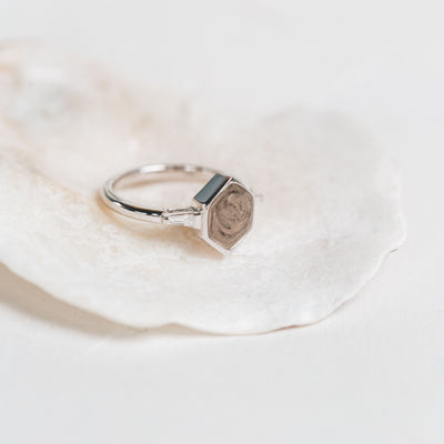 Pictured here is the 14K White Gold Hexagon White Baguette Diamond Band Ring by close by me jewelry on a white shell with a slightly blurry background 
