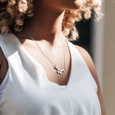 Pictured here is close by me jewelry's flower necklace designed to look like a Cluster of Hydrangeas with cremains in Sterling Silver around a model's neck