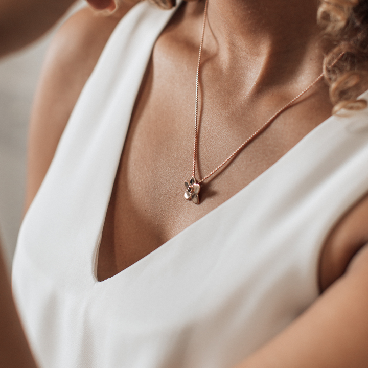 Pictured here is the Hydrangea Flower Cremains Necklace designed in 14K Rose Gold and set with ashes by close by me jewelry around a model's neck