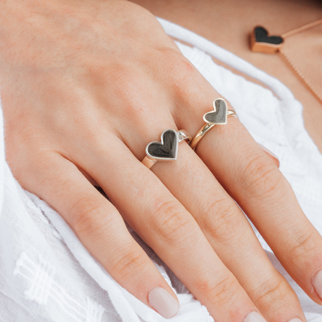 This photo shows a model wearing two pieces of Sterling Silver Heart Ashes Jewelry from close by me jewelry. The Imprint Heart Ashes Ring is on her middle finger and the Signature Heart Stackable Band Ashes Ring is on her index finger.