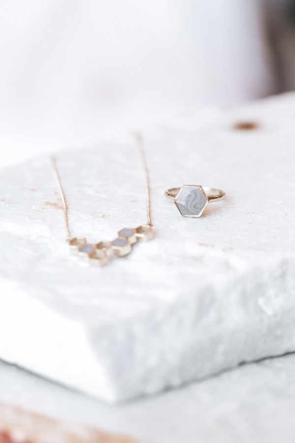 This is a stylized photo of the Large Hexagon Stacking Ring and Hexagon Cluster Pendant designs in 14K Yellow Gold by close by me