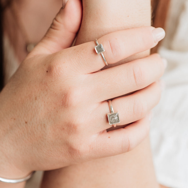 This photo shows a model wearing the Small and Large Square Stacking Ashes Rings in Sterling Silver on her index and ring finger