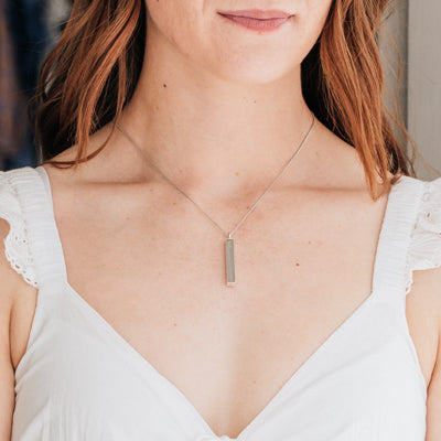 Pictured here is the Sterling Silver Long Bar Cremated Remains Necklace designed and set with ashes by close by me jewelry around a model's neck