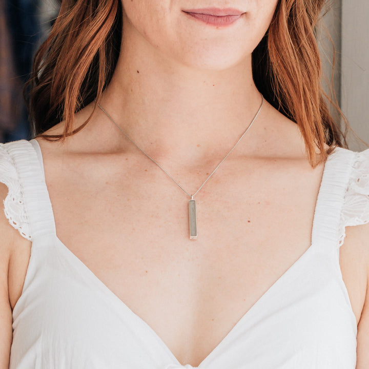 Pictured here is the Sterling Silver Long Bar Cremated Remains Necklace designed and set with ashes by close by me jewelry being worn around a model's neck