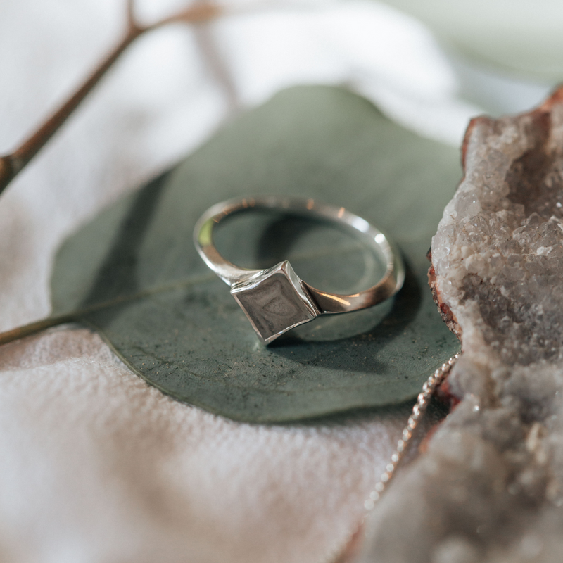 This photo shows the Luminary Ashes Ring in Sterling Silver by close by me jewelry lying flat on a leaf
