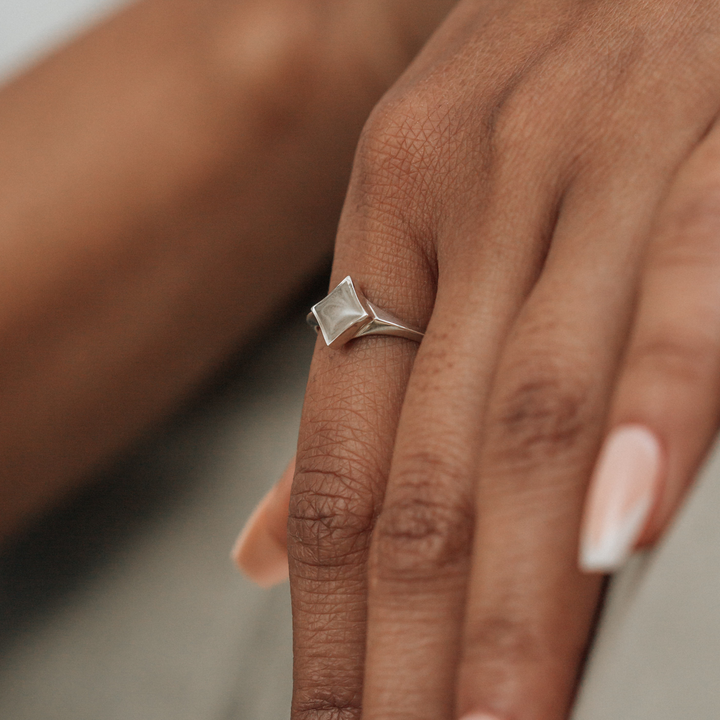 A close-up photo of a model's hand, wearing Close By Me's Sterling Silver Luminary Cremation Ring.