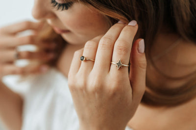 This photo shows close by me jewerly's North Star Cremation Ring design in 14K Yellow Gold being worn on a light-skinned model's index finger