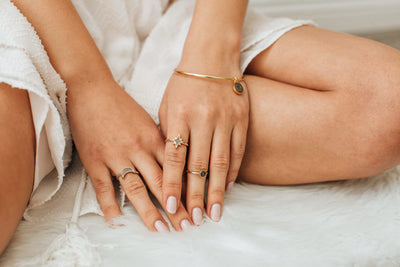 Pictured here are several pieces of cremation jewelry being worn by a light-skinned model. On the index finger of her left hand, she wears the 14K Yellow Gold North Star Ring
