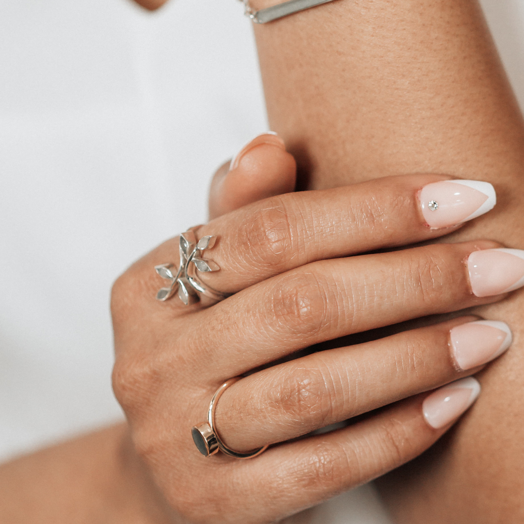 Pictured here is the Sterling Silver Olive Branch ashes ring design by close by me jewelry on a model's right index finger and paired with other ashes pieces