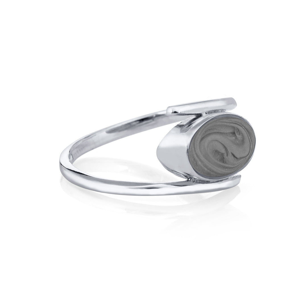 Pictured here is close by me jewelry's Oval Spiral Band Cremation Ring from the side to show its medium gray ashes setting and thickness of the bezel