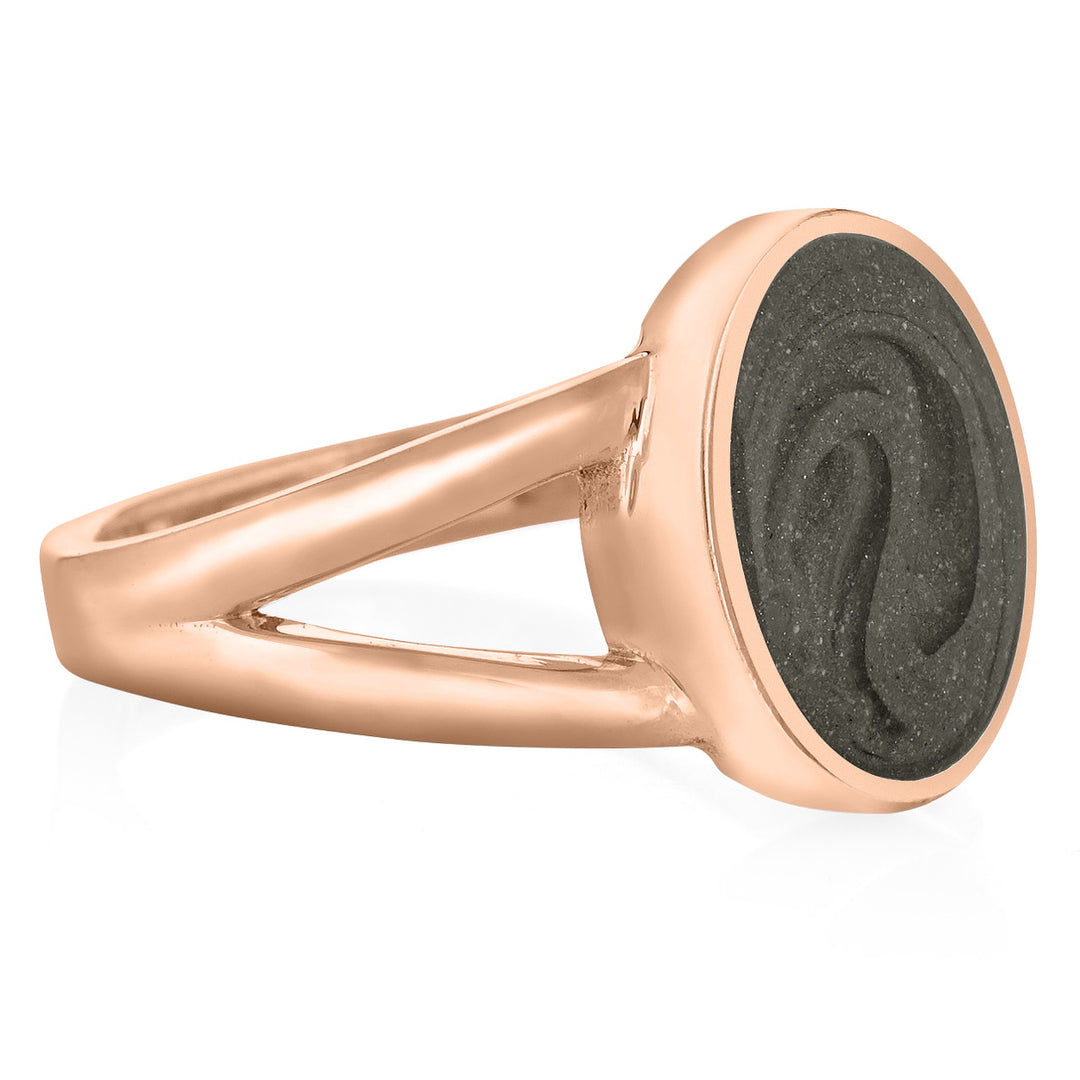 Pictured here is close by me jewelry's 14K Rose Gold Oval Split Shank Ashes Ring design from the side to show its medium grey cremation setting, split shank opening, and thickness of the bezel