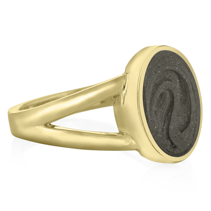 Pictured here is close by me jewelry's 14K Yellow Gold Oval Split Shank Ashes Ring design from the side to show its medium grey cremation setting, thickness of the bezel, and split band