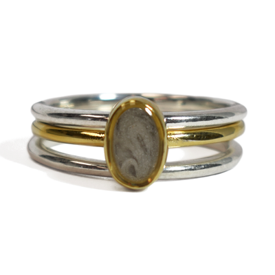 This photo shows the Mixed Metal Stacking Cremation Ring set designed by close by me jewelry with a 14K Yellow Gold Oval Stacking Ring with ashes between two Sterling Silver Smooth Companion Rings from the front