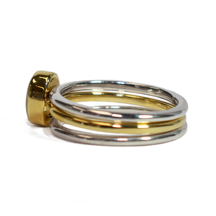 This photo shows the Mixed Metal Stacking Cremation Ring set designed by close by me jewelry with a 14K Yellow Gold Oval Stacking Ring with ashes between two Sterling Silver Smooth Companion Rings from the left side