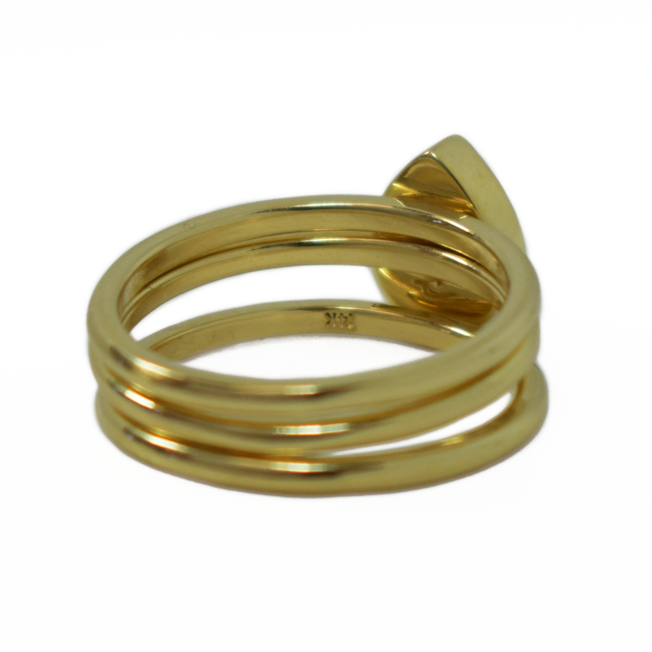 This photo shows a stacking set in 14K Yellow Gold with a Pear Ashes Stacking Ring in the center, designed by close by me jewelry, from the back at an angle to the right