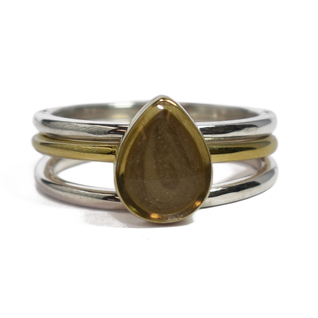 This photo shows close by me jewelry's mixed metal stacking set with a Pear Ashes Stacking Ring in 14K Yellow Gold and two Sterling Silver Smooth Companion Rings from the front
