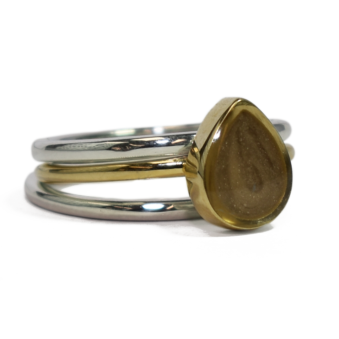 This photo shows close by me jewelry's mixed metal stacking set with a Pear Ashes Stacking Ring in 14K Yellow Gold and two Sterling Silver Smooth Companion Rings from the front at a slight angle to the right