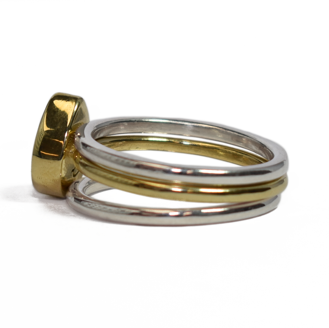 This photo shows close by me jewelry's mixed metal stacking set with a Pear Ashes Stacking Ring in 14K Yellow Gold and two Sterling Silver Smooth Companion Rings from the left side