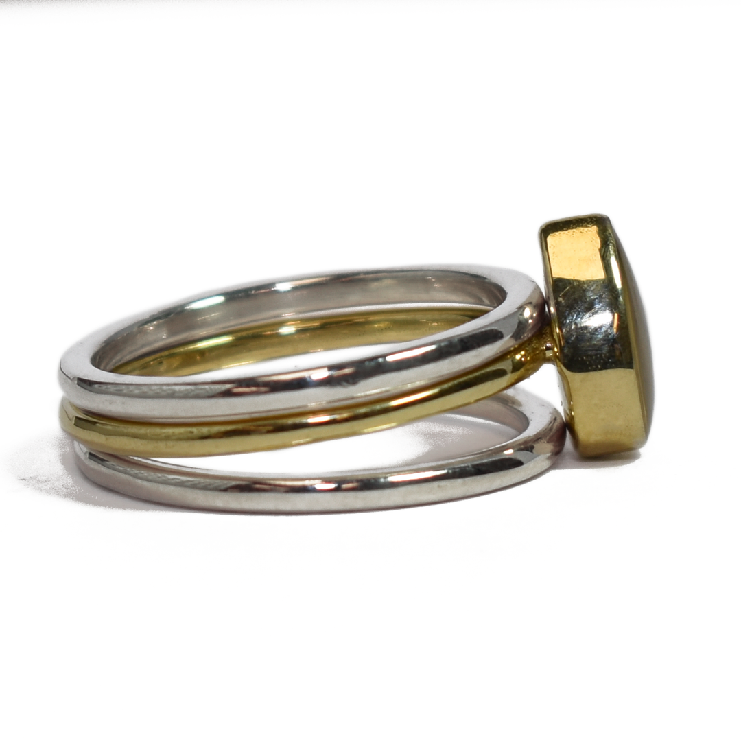 This photo shows close by me jewelry's mixed metal stacking set with a Pear Ashes Stacking Ring in 14K Yellow Gold and two Sterling Silver Smooth Companion Rings from the right side