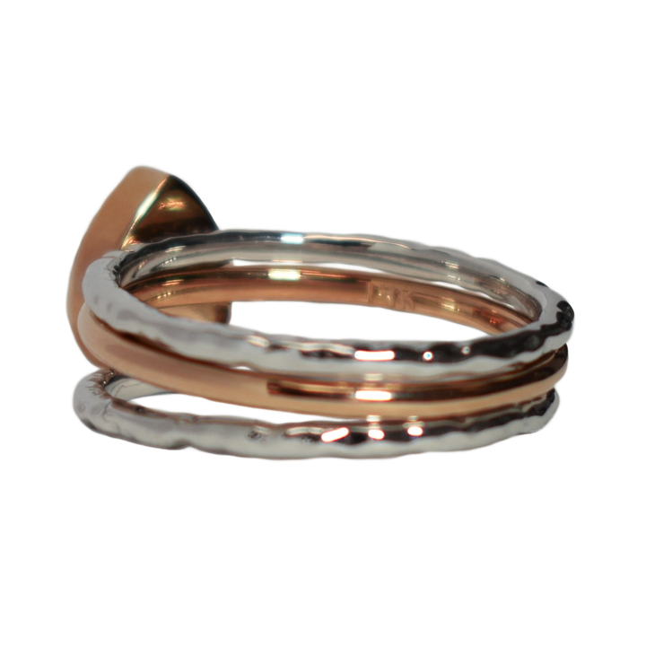 This photo shows the Pear Cremation Stacking Ring in 14K Rose Gold paired with two 14K White Gold Textured Companions to create one of close by me jewelry's ashes stacking ring sets from the back at a slight angle to the left