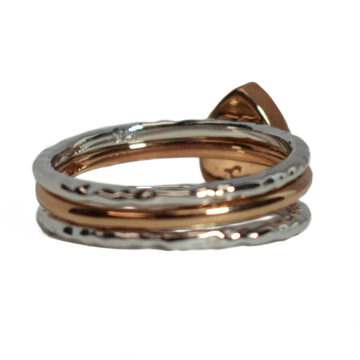 This photo shows the Pear Cremation Stacking Ring in 14K Rose Gold paired with two 14K White Gold Textured Companions to create one of close by me jewelry's ashes stacking ring sets from the back from a slight angle to the right