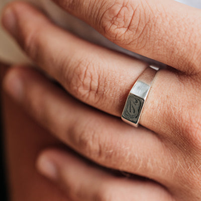 This photo shows a close up of the Men's Rectangle Signet Ring design in Sterling Silver on a male model's finger