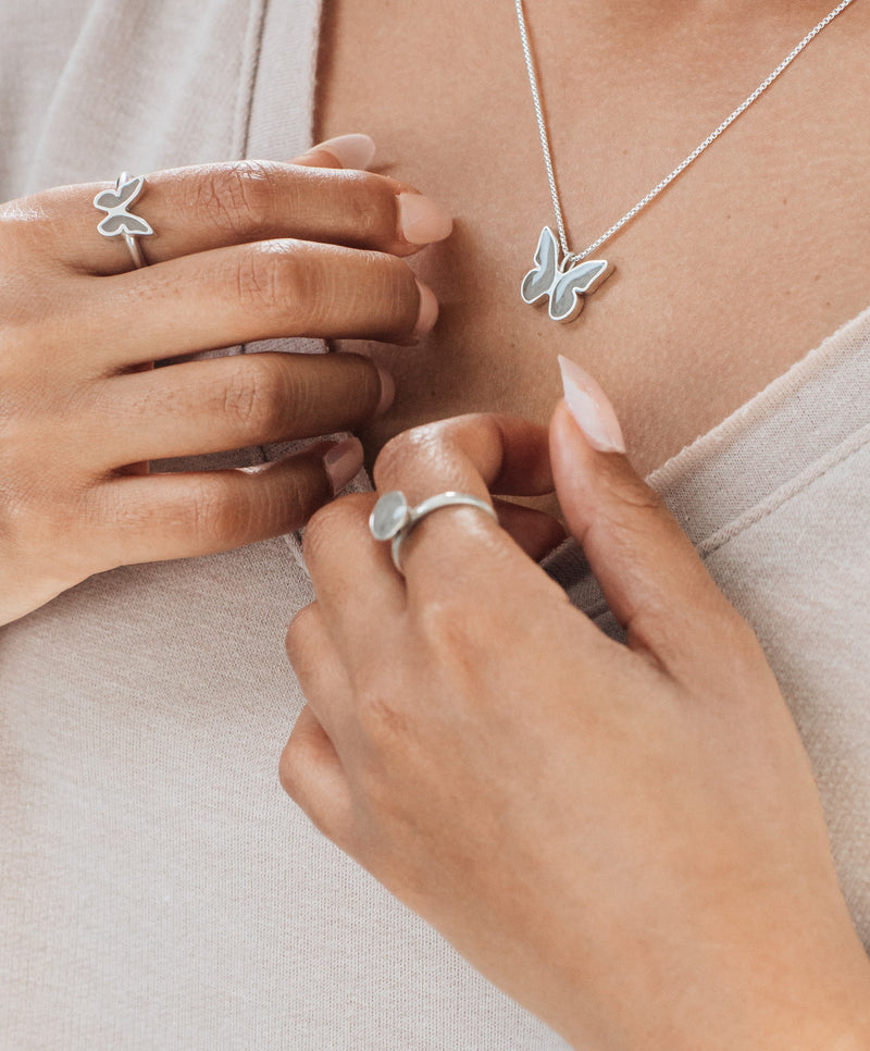 Pictured here is a model wearing Sterling Silver Jewelry with ashes designed by close by me jewelry; on her index finger, she wears the Signature Lotus Stackable Band Cremated Remains Ring