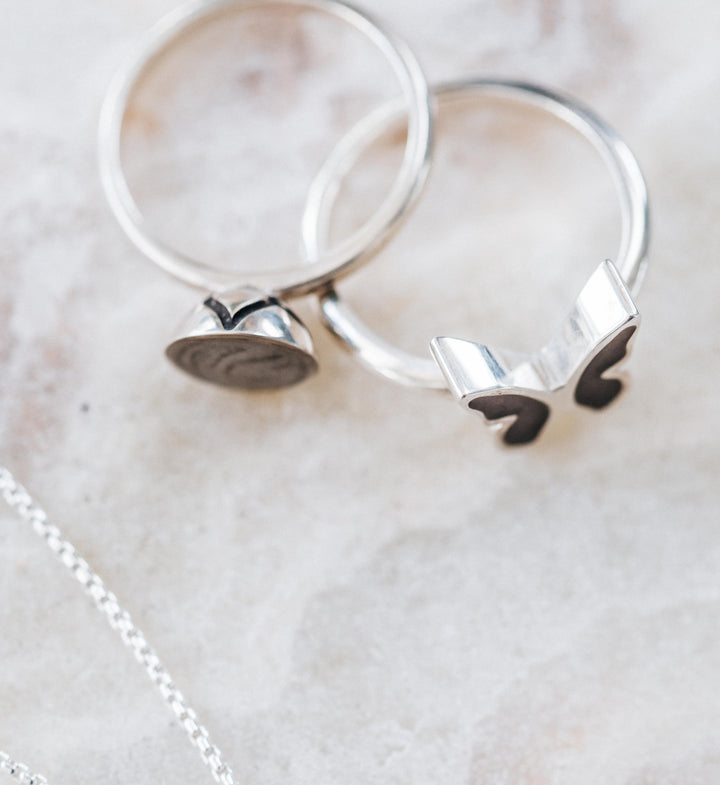 This photo shows the Signature Lotus Stackable Band and Butterfly Cremains Rings in Sterling Silver designed by close by me jewelry from the top