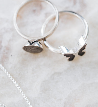 This photo shows a top view of both the Signature Lotus Stackable Band and Butterfly Ashes Rings in Sterling Silver, designed by close by me jewelry