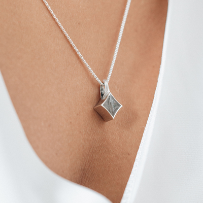 This photo shows a close up of a model wearing close by me jewelry's Sterling Silver Luminary Pendant with ashes
