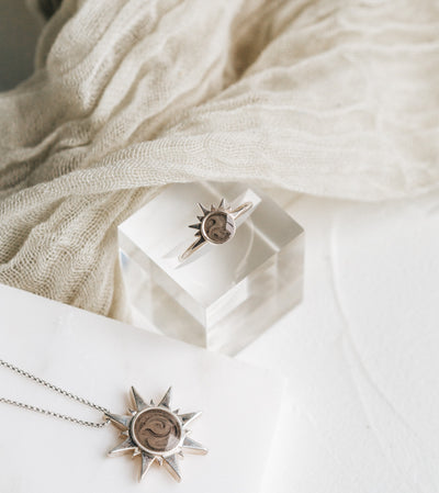 This photo shows several of close by me jewelry's Sterling Silver ashes pieces with Sun motifs lying flat on a multi-textured white background