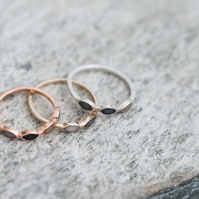 Pictured here are several ashes rings by close by me jewelry in mixed metals lying on a flat gray stone