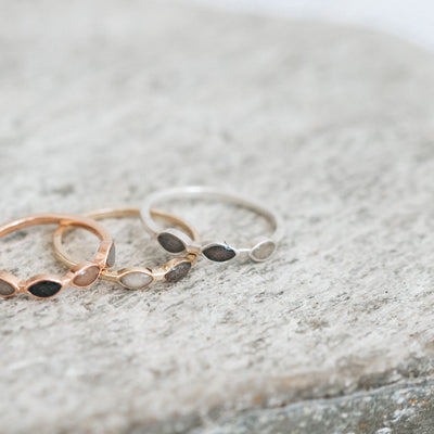 This photo shows several pieces of mixed metal cremation jewelry by close by me jewelry on a flat gray stone